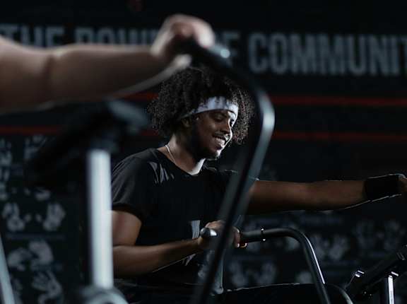 A person is working out on a stationary bike in a dark gym.