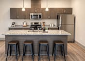 Thumbnail 5 of 10 - A kitchen with a granite countertop and bar stools.