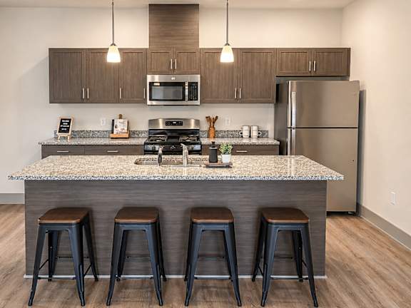 A kitchen with a granite countertop and bar stools.