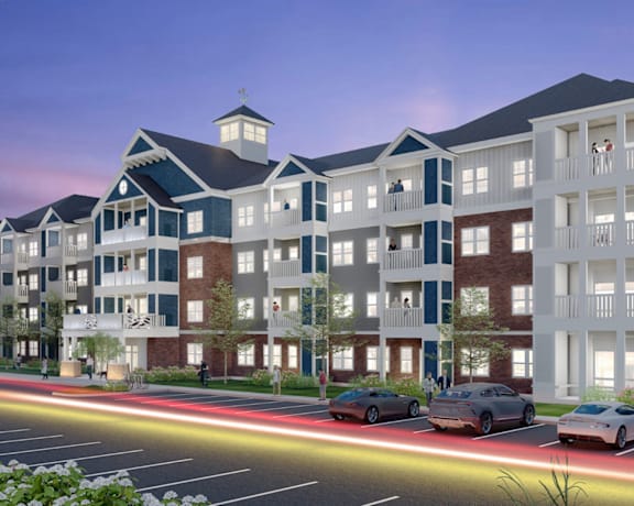 A modern apartment complex with cars parked in front.