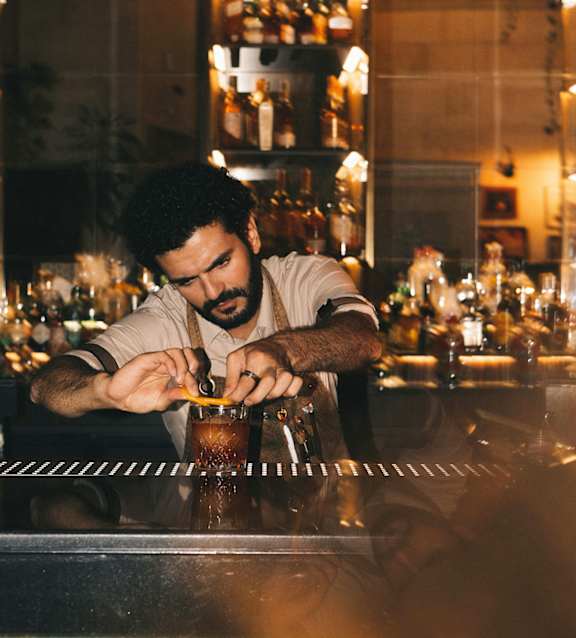 A bartender is making a drink at the bar.