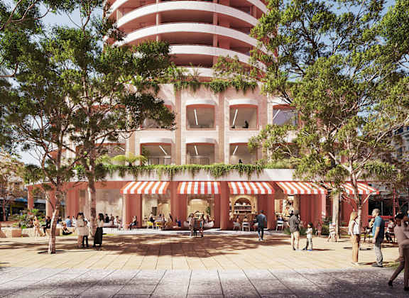 A white building with balconies and windows is surrounded by trees.