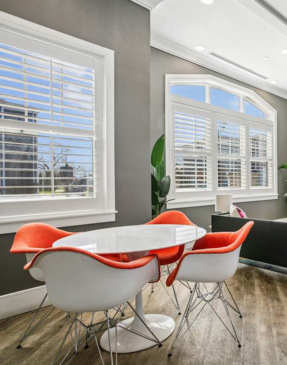 A modern dining room with a round table and orange chairs.