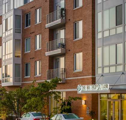 an apartment building on a city street at dusk at The Metropolitan Downtown Columbia, Maryland, 21044
