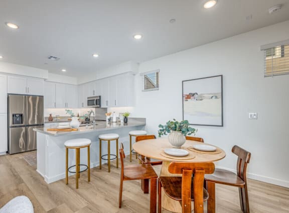 A kitchen with a refrigerator, microwave, and two bar stools.