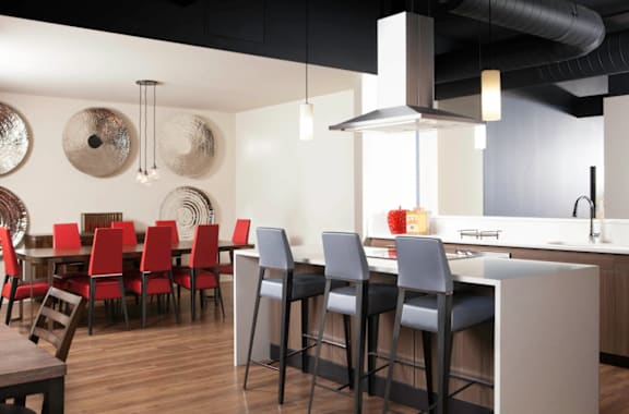 A modern kitchen with red chairs and a wooden table at Skye at Belltown Apartments in Washington 98121