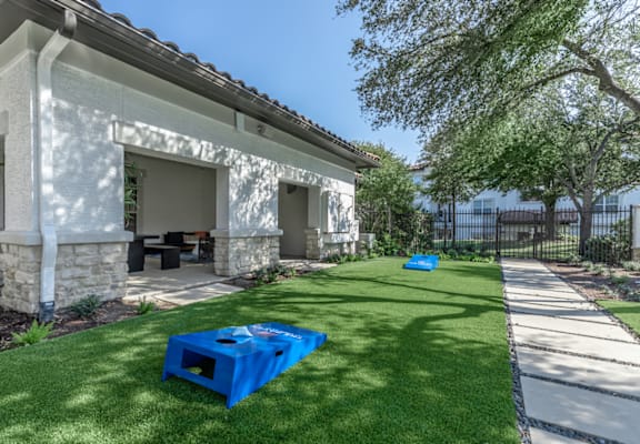 A blue plastic container is placed on a green lawn in front of a house.