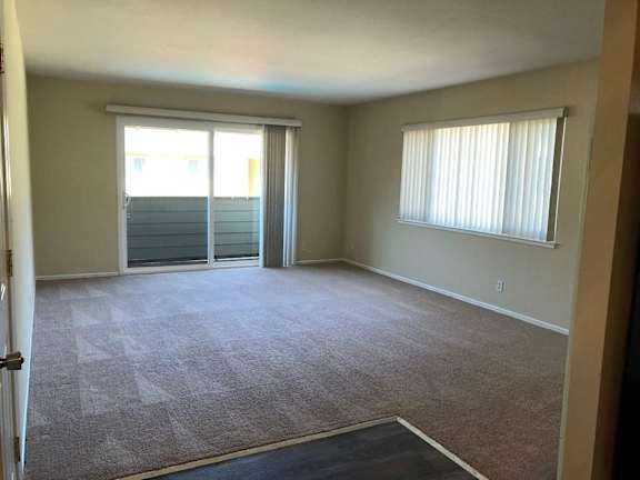 A room with a carpet floor and a window with blinds.