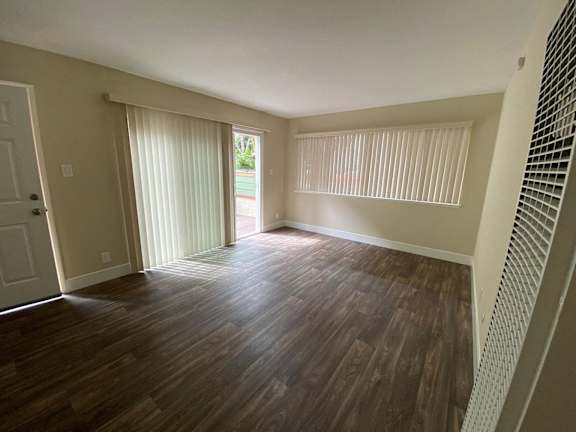 an empty living room with wood floors and a sliding glass door