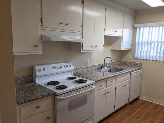 A kitchen with white cabinets and a granite countertop.