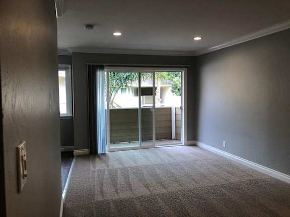 A room with wooden floors and a window with blinds.