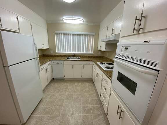 A kitchen with white appliances and cabinets.