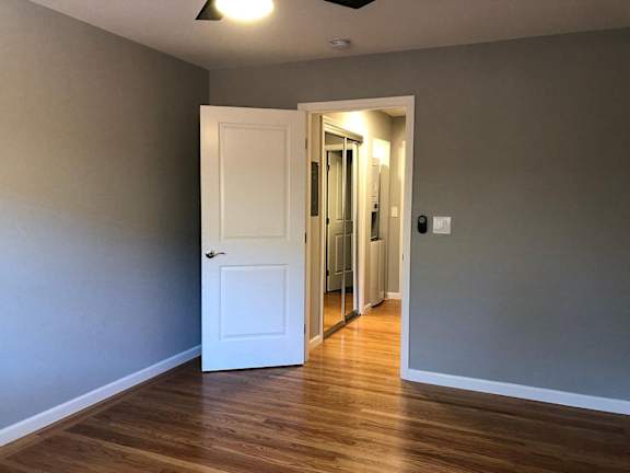 A room with a white door and wooden floor.