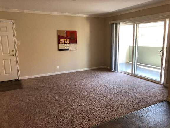 A room with wooden floors and a window with blinds.