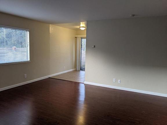 A room with wooden floors and a window with blinds.