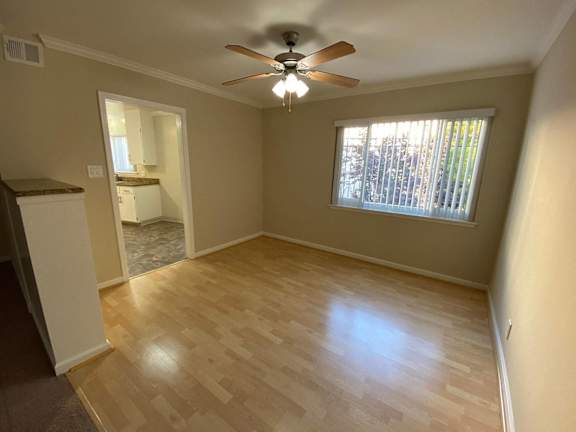 A room with a ceiling fan and wooden flooring.