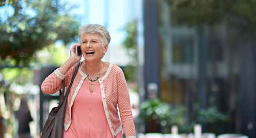 an older woman walking down the street talking on a cell phone