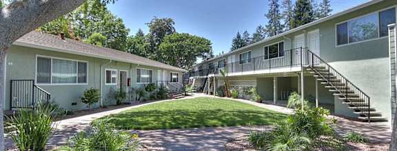 A sunny day at the apartment complex with green grass and trees.