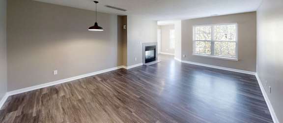 A spacious room with wooden flooring and a television set.