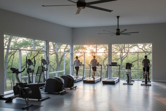 A gym with people exercising and a ceiling fan.