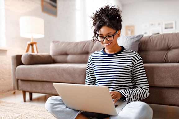 a woman sitting on the floor using a laptop computer in her living room