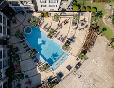 A swimming pool surrounded by a sandy area and a building.