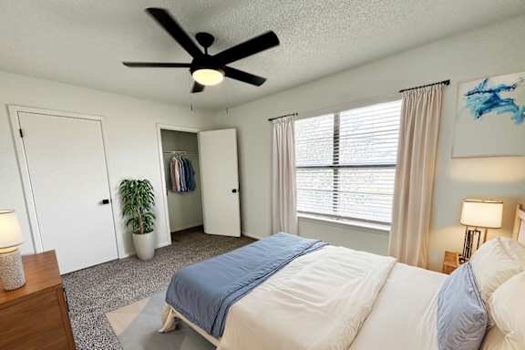 A bedroom with a large bed and a ceiling fan.