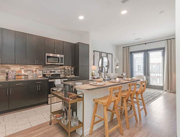 A modern kitchen with dark wood cabinets and a central island  at Bridges at Flatiron, Broomfield, 80021