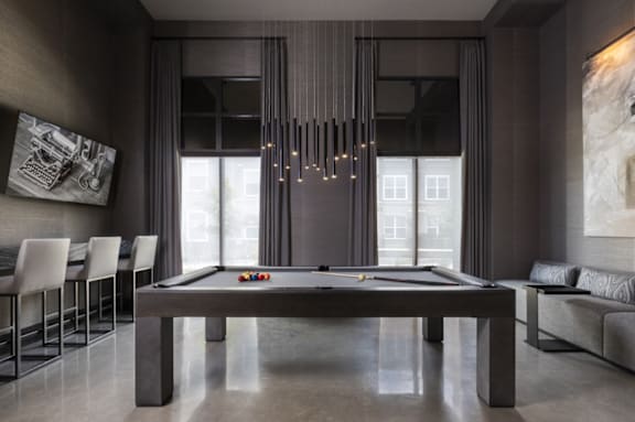 A pool table is in the middle of a room with a long table and chairs.