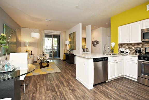 A modern kitchen with white cabinets and a wooden floor at The Kitt at Warner Center in Woodland Hills, 91303