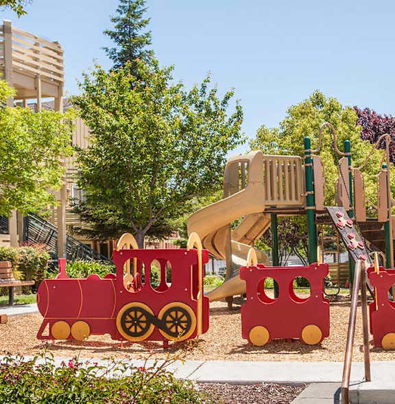A playground with a red train and a slide at The Woods Apartments, San Jose, CA, 95136