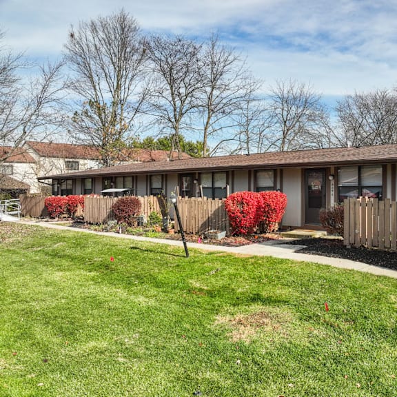 A house with a brown roof and a white picket fence.