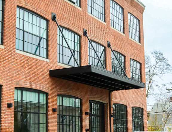 A red brick building with a black awning and a black metal fence.
