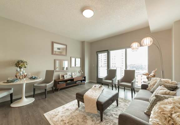 A living room with a grey couch, a white table, and a large window.