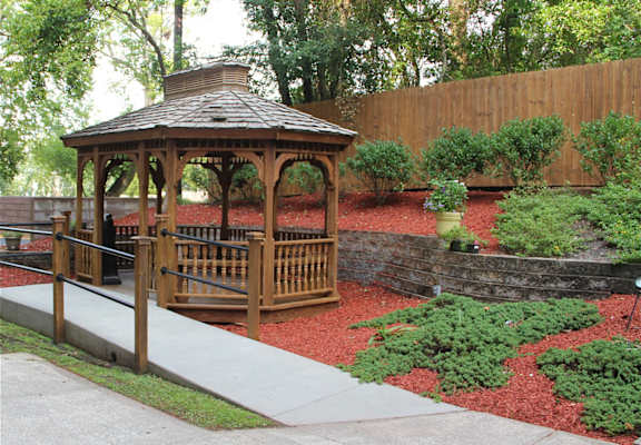 A gazebo is surrounded by a wooden fence and a stone wall.