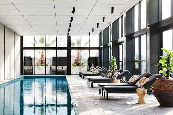 A large indoor swimming pool with lounge chairs and plants.