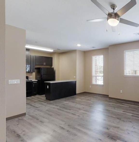 A spacious room with a ceiling fan and wooden flooring.
