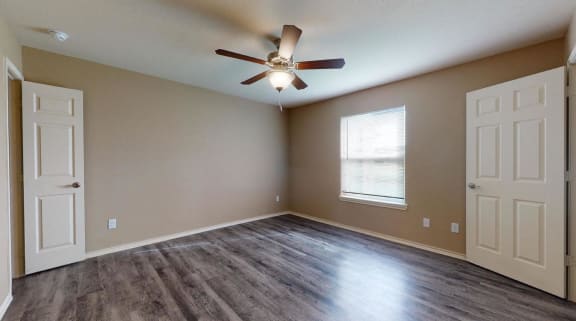 an empty living room with a ceiling fan and a window