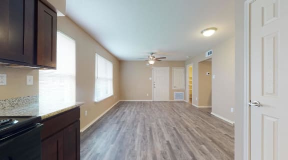 an empty living room and kitchen with a ceiling fan