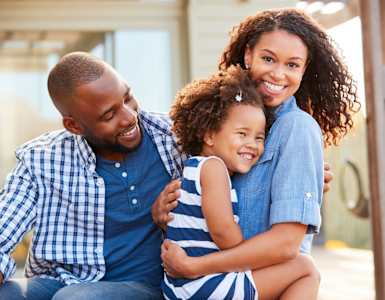 A family of three is sitting together outside.