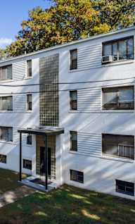 A white apartment building with a green lawn in front.at Greenbelt Properties, Maryland