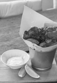 A metal cup filled with fried food next to a small bowl of sauce.