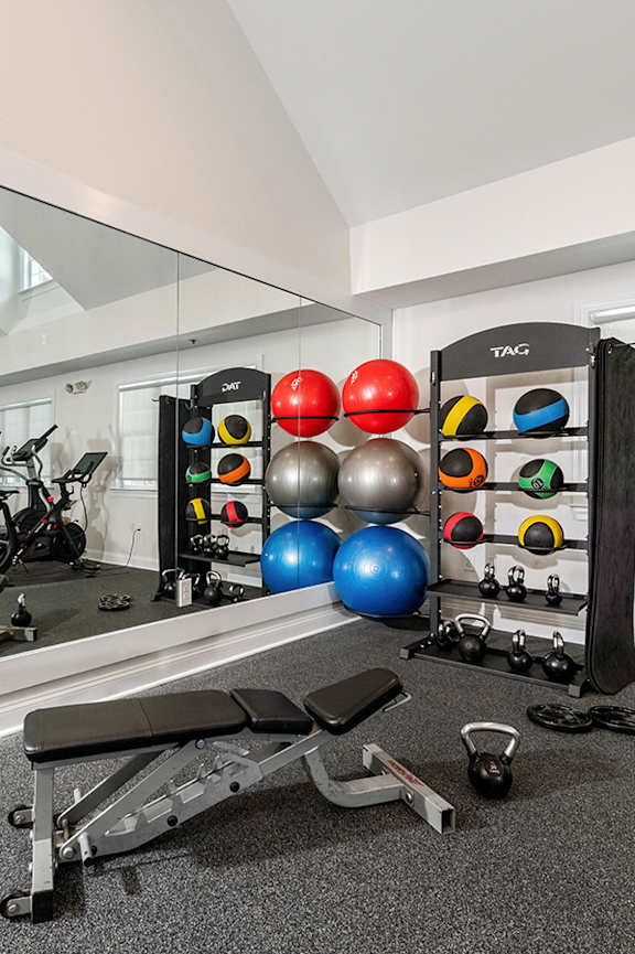 A gym room with a mirror, weights, and exercise equipment. at Spa Cove Apartments, Annapolis, 21403