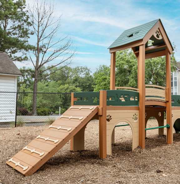 A wooden playground structure with a green roof and a slide.