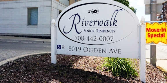 A sign for Riverwalk Senior Residences is displayed in front of a building.