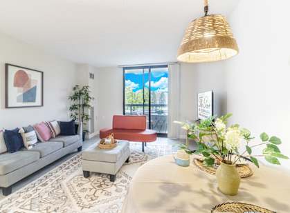 A living room with a grey couch, a red chair, a coffee table, and a large window.