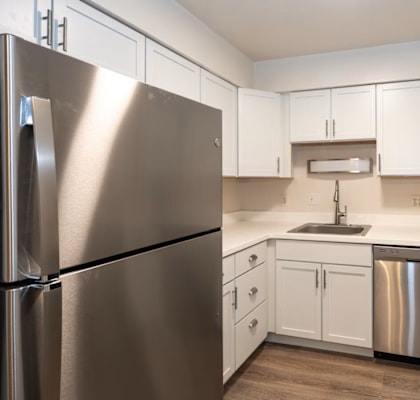 A kitchen with a stainless steel refrigerator and white cabinets.