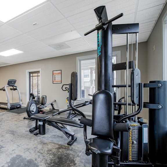 A gym with a variety of equipment including treadmills, weights, and exercise machines.