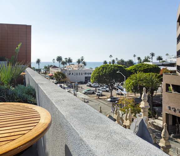 A patio with a table and chairs overlooks a street.