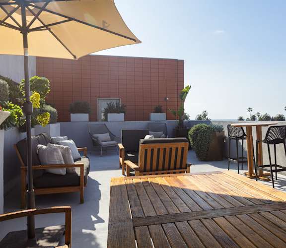 A patio with a table, chairs, and a yellow umbrella.